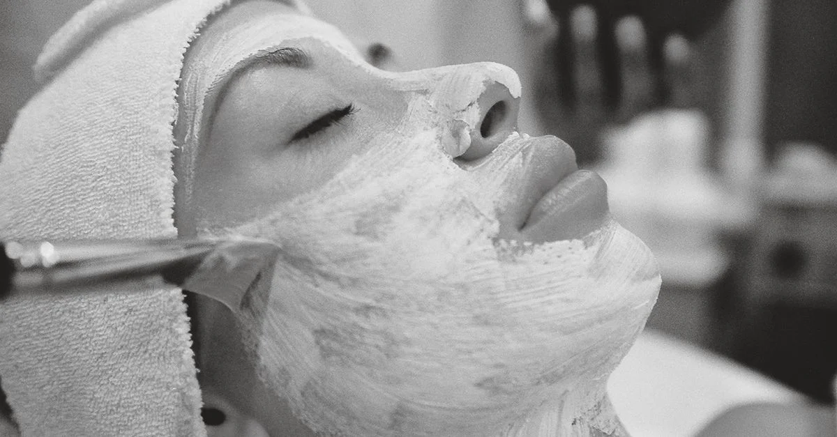 Une femme reçoit un masque facial rajeunissant dans un spa pour des soins de la peau.