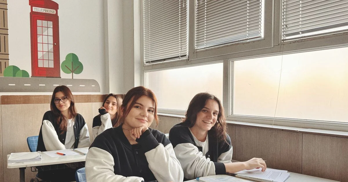 Groupe d'étudiants dans une salle de classe au décor britannique, étudiant près d'une grande fenêtre.